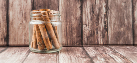 Cinnamon stick spices in a mason jar over weathered wooden backgroundの写真素材