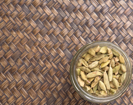 Cardamom spices in a mason jar over wicker backgroundの写真素材
