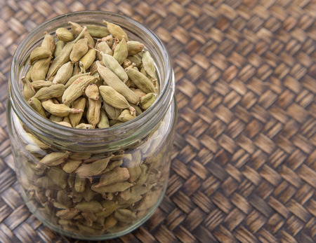 Cardamom spices in a mason jar over wicker backgroundの写真素材