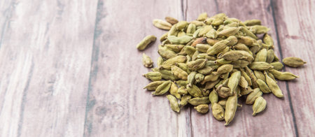 Cardamom spice in a white bowl over weathered wood background