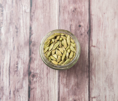 Cardamom spice in a mason jar over weathered wood background