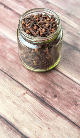 Clove spice in a mason jar over weathered wooden backgroundの写真素材