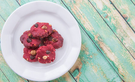 Homemade red velvet flavor cookies in white plate over weathered light green colored wooden backgroundの写真素材