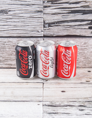 PUTRAJAYA, MALAYSIA - JULY 5TH, 2015. Coca Cola cans on aged wooden background. Coca Cola drinks are produced and manufactured by The Coca-Cola Company, an American multinational beverage corporation.のeditorial素材