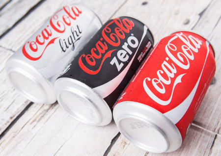 PUTRAJAYA, MALAYSIA - JULY 5TH, 2015. Coca Cola cans on aged wooden background. Coca Cola drinks are...