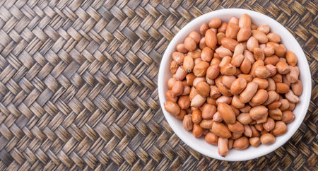Ground nut or peanuts in white bowl over wicker background