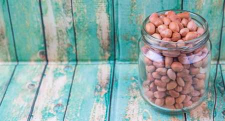 Ground nut or peanuts in a mason jar over weathered wooden backgroundの写真素材