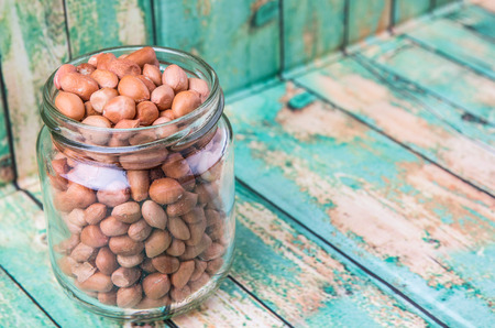 Ground nut or peanuts in a mason jar over weathered wooden backgroundの写真素材