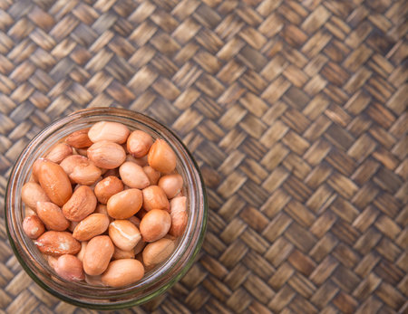 Ground nut or peanuts in a mason jar over wicker background