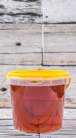 Honey in a plastic bucket over rustic aged wooden backgroundの写真素材