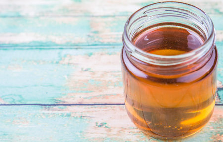 Honey in a mason jar over rustic weathered wooden backgroundの写真素材
