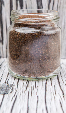 Dried processed tea leaves in a mason jar over rustic weathered wooden background