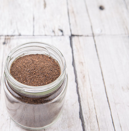 Dried processed tea leaves in a mason jar over rustic weathered wooden background