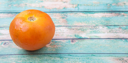 Orange tomato over weathered wooden backgroundの写真素材