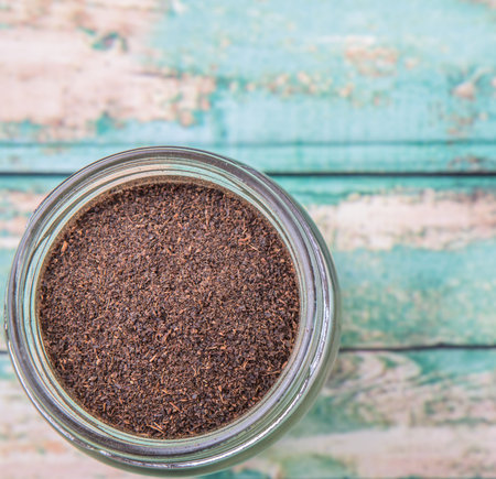 Dried processed tea leaves in a mason jar over rustic weathered wooden backgroundの写真素材