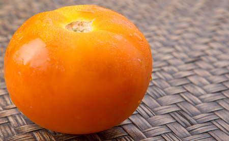 Orange tomato over wicker backgroundの写真素材