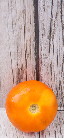 Orange tomato over weathered wooden backgroundの写真素材