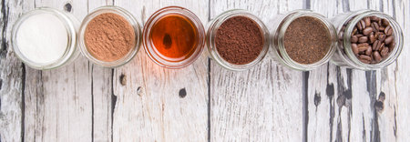 Coffee beans, coffee powder, creamer, cocoa powder, honey and processed tea leaves in mason jars over weathered wooden backgroundの写真素材