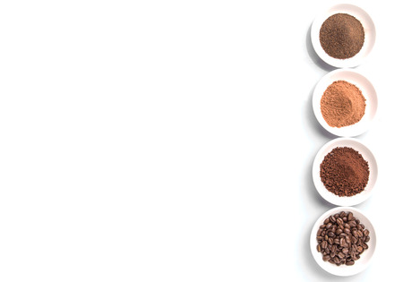 Coffee beans, powdered coffee, chocolate powder and processed tea leaves beverages in white bowls over white backgroundの写真素材