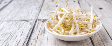 Bean sprouts in white bowl over weathered wooden backgroundの写真素材