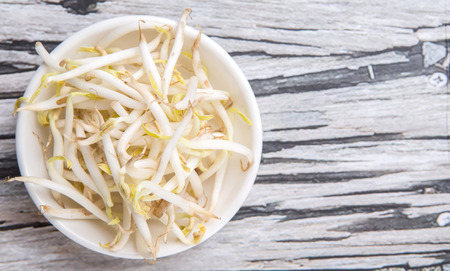 Bean sprouts in white bowl over weathered wooden backgroundの写真素材
