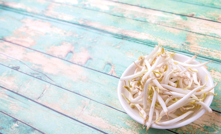 Bean sprouts in white bowl over weathered wooden backgroundの写真素材