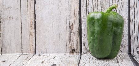 Fresh green bell pepper on a rustic wooden backgroundの写真素材