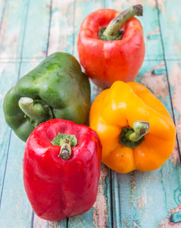 Fresh colorful bell peppers on a rustic wooden backgroundの写真素材