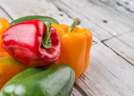 Fresh colorful bell peppers on a rustic wooden backgroundの写真素材