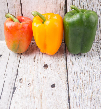 Fresh colorful bell peppers on a rustic wooden backgroundの写真素材