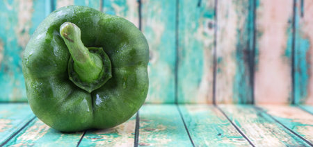 Fresh green bell pepper on a rustic wooden background