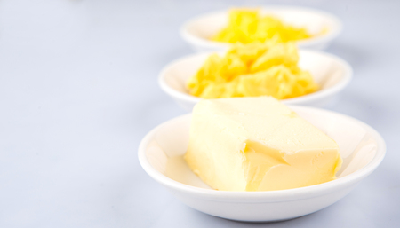 A block of butter, margarine and ghee in white bowlsの写真素材