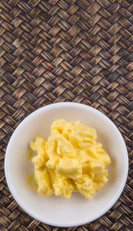 A bowl of margarine in white bowl over wicker backgroundの写真素材