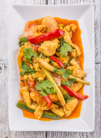 Malaysian traditional dish of Ayam Paprik or spicy stir fry chicken on white plate over wooden backgroundの写真素材
