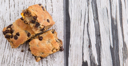 Sweet brownie dessert bar with chocolate chips over wooden background