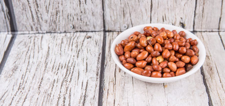 Deep fried peanuts in white bowl over rustic wooden backgroundの写真素材