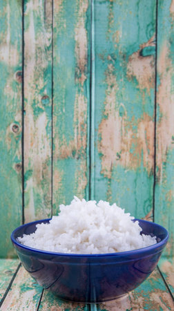 Cooked steamed rice in a blue bowl over wooden backgroundの写真素材