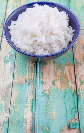 Cooked steamed rice in a blue bowl over wooden backgroundの写真素材