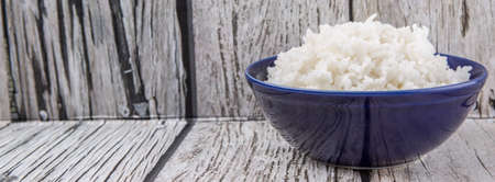 Cooked steamed rice in a blue bowl over wooden backgroundの写真素材