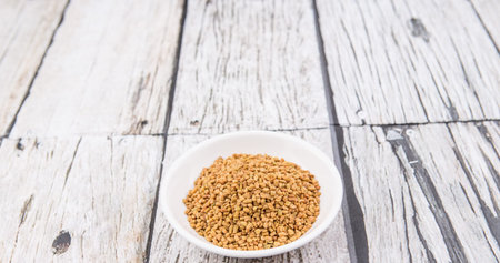 Fenugreek seeds in white bowl over wooden backgroundの写真素材