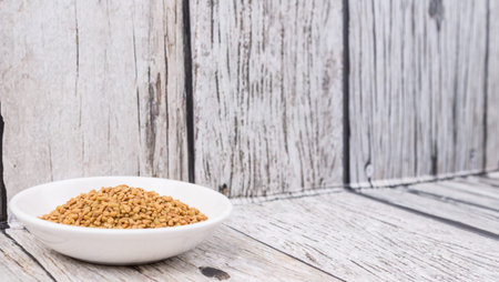 Fenugreek seeds in white bowl over wooden backgroundの写真素材