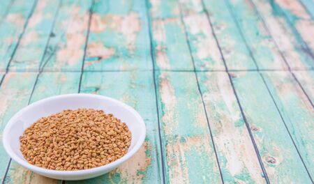 Fenugreek seeds in white bowl over wooden backgroundの写真素材