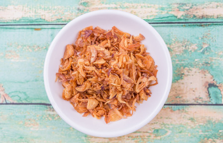 Deep fried shallots for garnishing in white bowl over wooden backgroundの写真素材