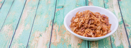 Deep fried shallots for garnishing in white bowl over wooden backgroundの写真素材