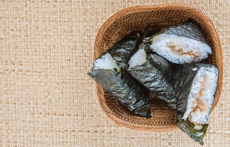 Popular Japanese rice ball wrapped with seaweed or locally known as onigiri over wicker backgroundの写真素材