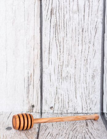 Wooden honey dipper over wooden backgroundの写真素材