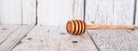 Wooden honey dipper over wooden backgroundの写真素材