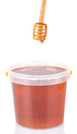 Honey dipper with natural honey over white backgroundの写真素材