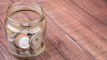 Japanese Yen coins in a mason jar over wooden background
