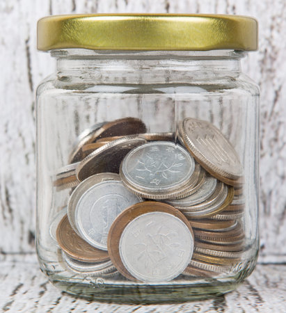 Japanese Yen coins in a mason jar over wooden background